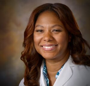 Headshot of Carlesa Pierre, a certified Family, Adult and Geriatric Nurse Practitioner for the Center for Living Well - Epcot, wearing a white lab coat