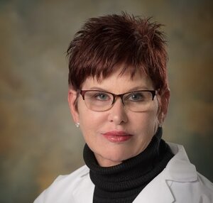 Headshot of Martha McCabe, board-certified Physician Assistant at the Center for Living Well - Celebration, wearing a white lab coat and glasses