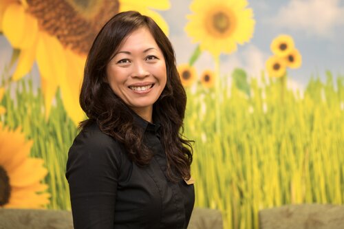 Photo of Natalie Tran Le, Pharmacist at the Center for Living Well, in front of a background of sunflowers