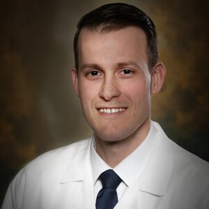Headshot of Dr. Ryan Nicholas, a board-certified Optometrist for the Center for Living Well - Celebration, wearing a white lab coat and navy blue tie